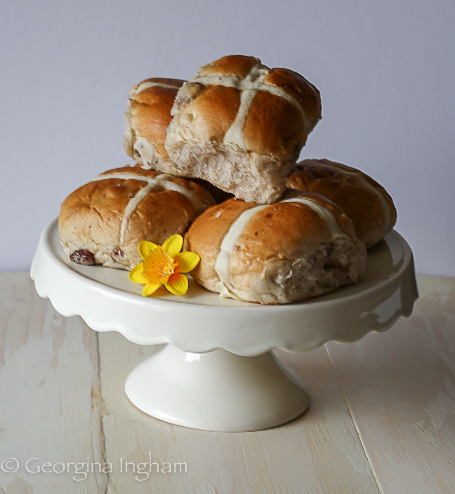 Traditional hot cross buns on a cake stand &ndash; homemade British spiced fruit buns with piped crosses